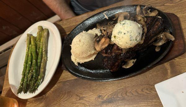 Alpha cut strip steak with sautéed mushrooms, garlic butter, mashed potatoes, and asparagus. All toppings are extra, as is the asparagus.