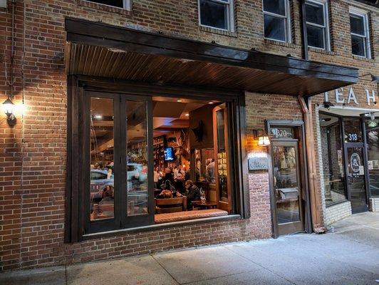 Outside. Storefront at night. Low key. The Crunkleton is located between Tropical Smoothie Cafe (The Book Shop) and Tea Hill (Cha House).