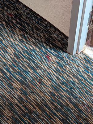 Red stains  throughout the carpet.