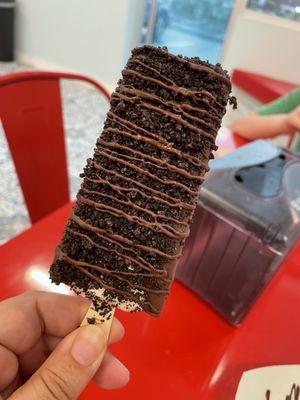 Coconut paleta, coated in chocolate, rolled in Oreos, drizzled with chocolate