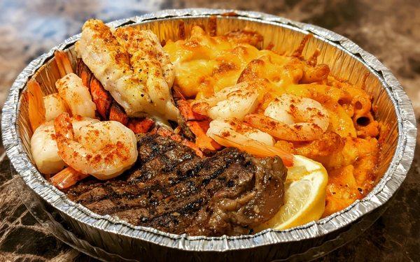 Steak, lobster tail, and shrimp with two sides of mac and cheese.