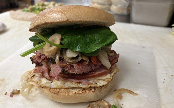 Egg Sandwich with Pastrami, Ham, Mushroom, Onion and Spinach on a bagel