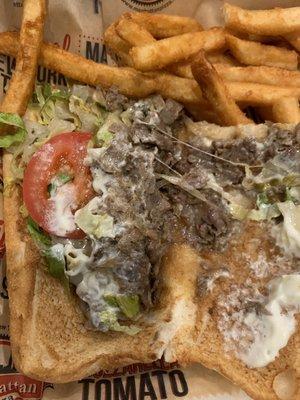 Sparse cheesesteak with a single miniature tomato, brown lettuce and very little meat.