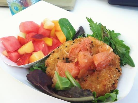 Thai curry crab cake with grape fruit on a bed of greens and a side of fresh fruit.