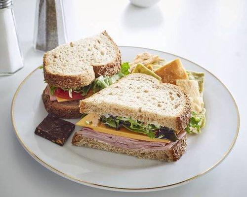 Ham, Cheddar Cheese, Lettuce, Tomato, with Mayonnaise on Whole Wheat bread or Herb Wrap. Served with house made chips and chocolate bark.