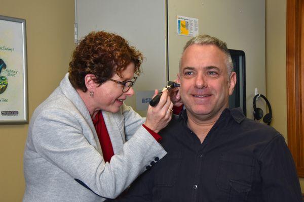 Hearing Instrument Specialist Jodi Weber inspecting a patient's ear.