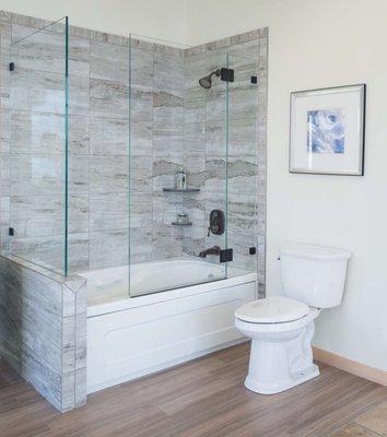 This custom shower enclosure features oil rubbed bronze hardware that matches the bathroom's fixtures.