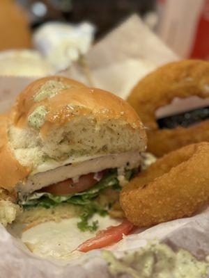 Chicken pesto sandwich with onion rings.