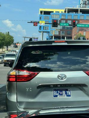 Vehicle with turn signal on and a traffic sign lit showing No Left Turns at a major intersection.