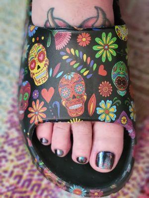 Pedicure with black gel polish and chameleon flake on top.