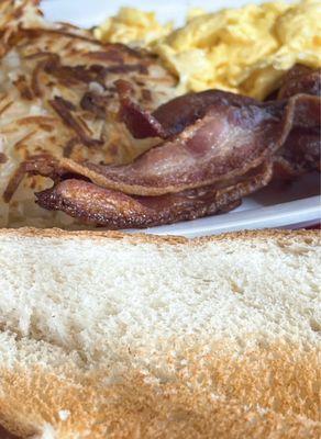 Scrambled eggs, hash browns, bacon and toast