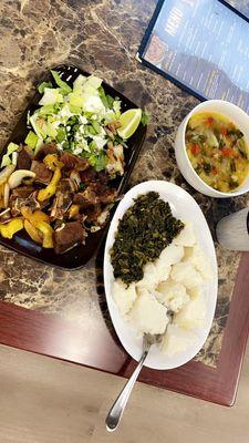 White plate: Ugali ( White corn meal ) and veggies Black plate: Goat meat and salad White bowl: Special soup mainly boiled vegetables