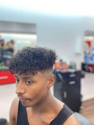 Natural curly sides, with a high-mid fade on the side.