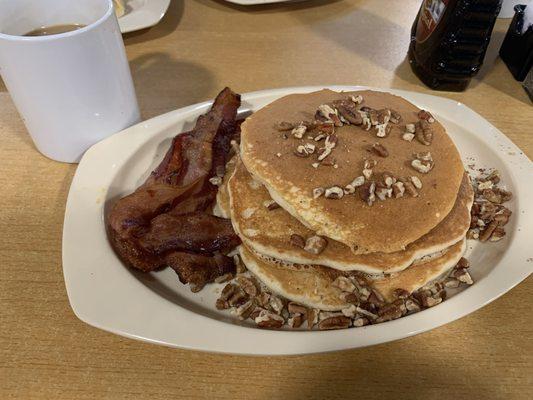 Pancakes with pecans and side of bacon.