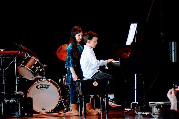 Victoria helps her brother Zecharia by standing with him at a 2019 performance