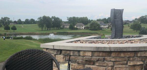 Seating near the fire pit with beautiful homes, well manicured lawns and a waterfall/fountain in the background.