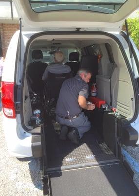 Strapping the wheelchair into the van for safety.