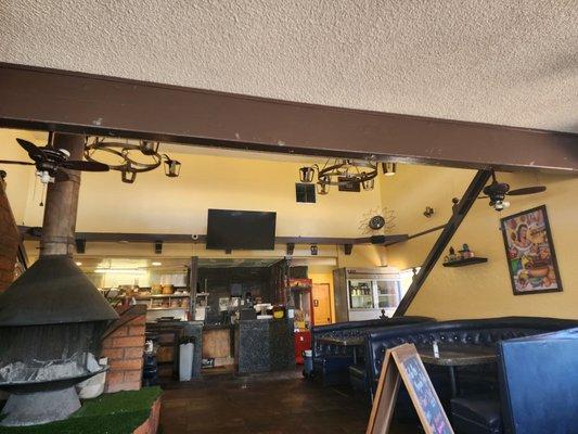 Interior of restaurant with metal stove, chandeliers,  paintings, booths for dining.