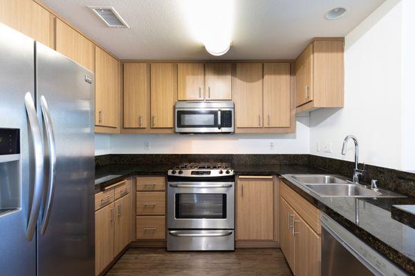 Modern kitchen with waterfall French door refrigerator, island, bar seating and marble style countertops and backdrops.