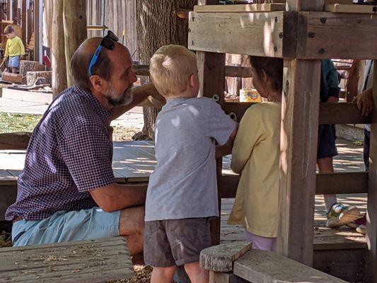 Grandparent helping to fix play structure with children's help. The children helped with using the tools.