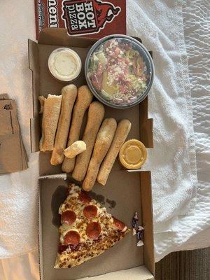 Lunch slice of pepperoni pizza, breadsticks with nacho cheese, and salad with ranch.