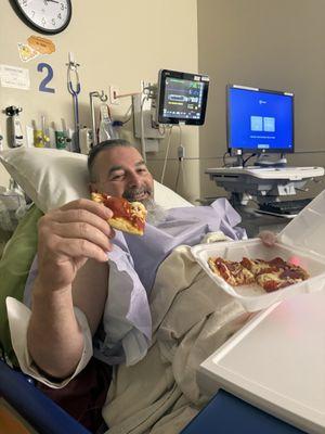 Happy patient recovering with a pepperoni pizza.