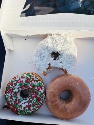 Clockwise: coconut donut, plain glazed donut,  Christmas sprinkled donut.