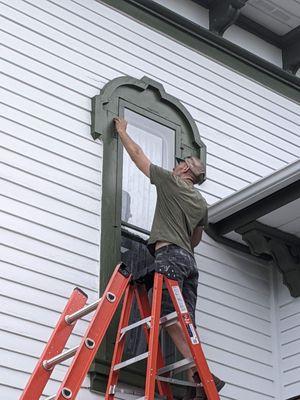 Installing a restored storm window on a historic home in Owatonna, Minnesota.