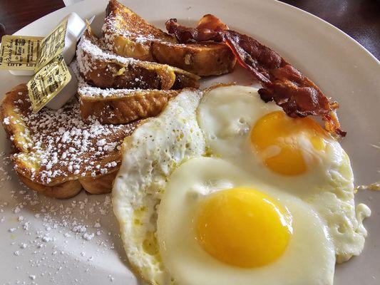 Breakfast Combo: eggs (sunny side up), choice of meat (bacon), and cooked item (French toast).