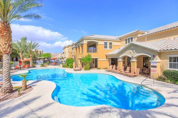 Full view of resort-style pool with palm trees and southwest-inspired property exterior.