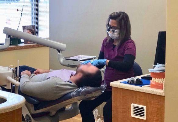 One of the hygienists performing a routine cleaning on a patient in order to maintain optimal tooth health