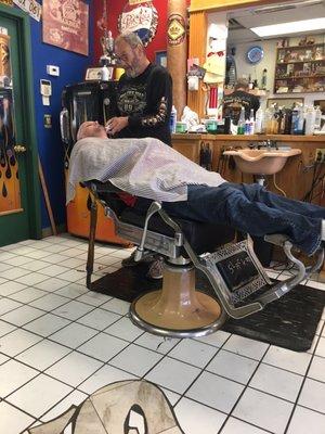 Getting his face trimmed before the straight razor.