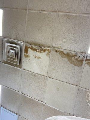 Dirty ceiling tiles over food and filthy vent.