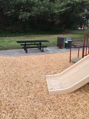 Two picnic tables and one small BBQ grill in the park