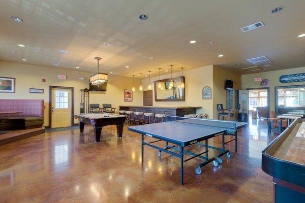 Tavern style game room with a ping pong table, shuffleboard, billiards table, and poker table. Residents can rent out this space for FREE!