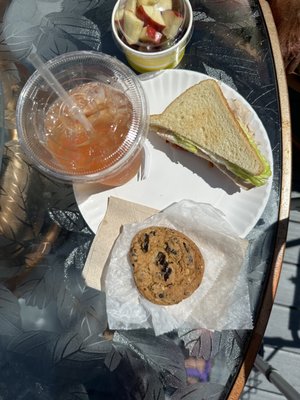 Half of a turkey sandwich, a side of fresh fruit, a delicious chunky chocolate chip cookie and fresh iced tea with a splash of lemonade.