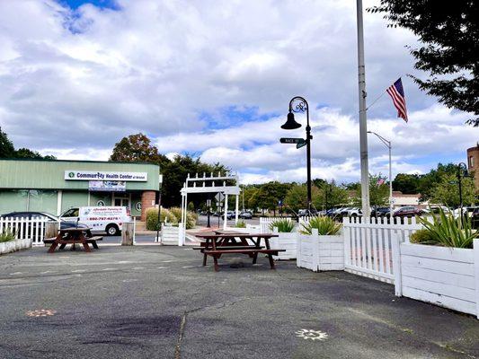 Some of their outdoor picnic seating in front and entrance to their area front the sidewalk