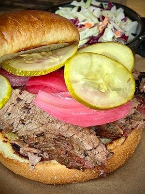 TEXAS BRISKET SANDWICH smoked brisket topped with pickled red onion and pickles on a griddled brioche bun with your choice of que and side