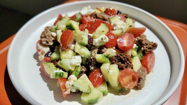 Dakos Salad: cherry tomatoes, cucumbers, Kalamata olives, red onion, feta (vegan available), carob croutons