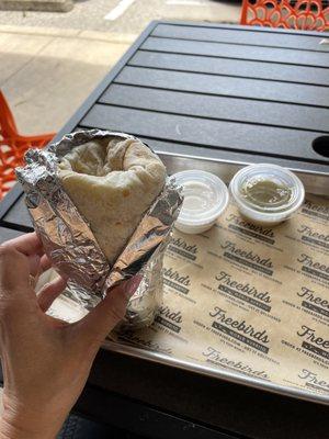 Green Chili Pork Burrito with a side of Sour Cream & Green Tomatillo Sauce.