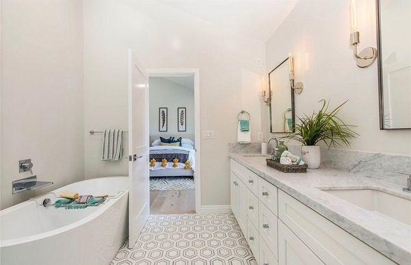 Shaker white vanity, quartz countertops, Spanish style flooring and stand alone tub.