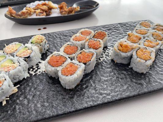 Spicy crab avocado roll, spicy tuna roll, and spicy yellowtail roll, plus soft shell crab appetizer in the background