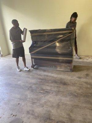 Protecting the piano with moving blankets and plastic wrap.