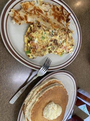 Meat, tomatoes and green peppers omelette home fries and short stack of pancakes.