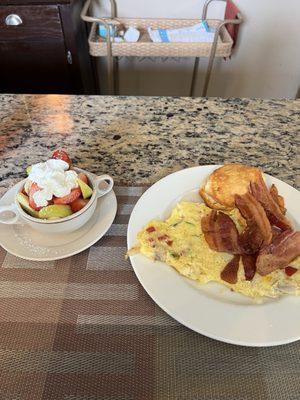 Mixed fruit and vegetable deluxe omelette with bacon and a biscuit.