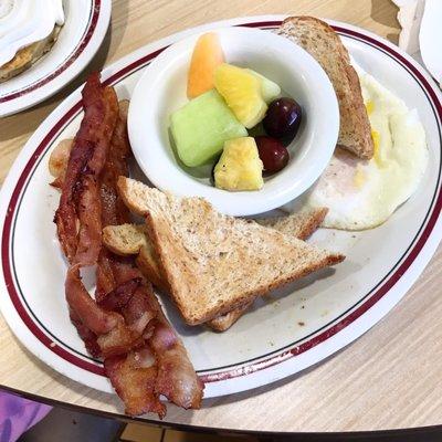 2 egg breakfast with bacon, wheat toast and fruits