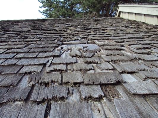 Wood cedar shake roof showing age and spits in shingles allowing water to drain / leak into the home's interior.