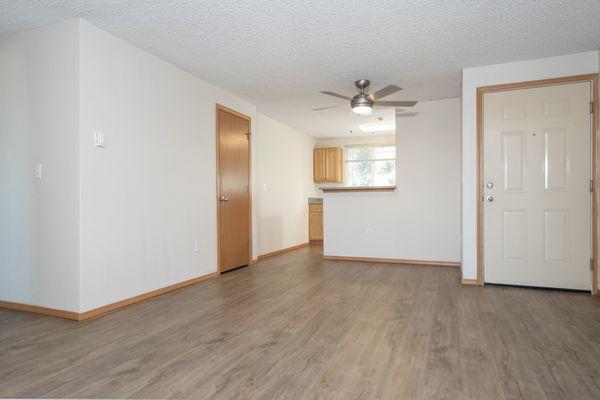 Other angle from living room looking at the front door, dining room with ceiling fan and closet space.