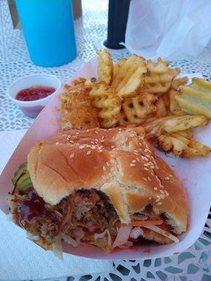 Pulled pork sandwich with pickles and coleslaw plus waffle fries.