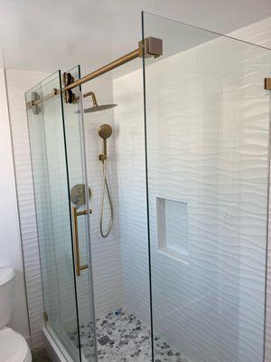 Single sliding shower door frameless with return panel, gold hardware.